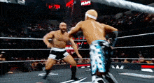 two men are wrestling in a ring with a crowd in the background .