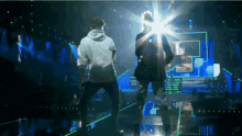 a man in a white hoodie is standing next to a woman in a black dress on a stage
