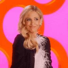 a woman in a black jacket with white feathers on the sleeves is smiling
