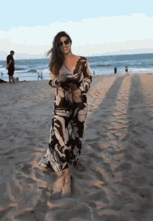 a woman in a black and white dress stands on the beach