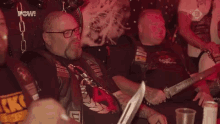 a group of men holding knives in a dark room .