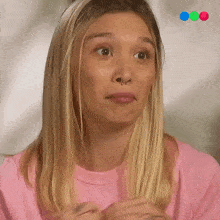 a woman with a nose ring is wearing a pink shirt and making a funny face