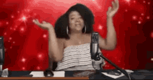 a woman is sitting in front of a microphone with her arms outstretched .