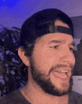 a man with a beard is wearing a black hat and making a funny face