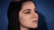 a close up of a woman 's face against a blue backdrop