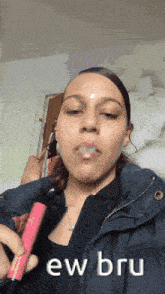 a woman in a black jacket is holding a pink lipstick in her hand and says ew bru on the bottom