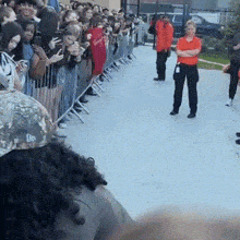a crowd of people are standing in front of a fence watching a person perform