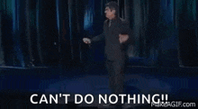 a man in a suit and tie is making a funny face and saying `` can 't do nothing ! ''