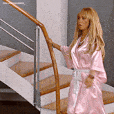 a woman in a pink robe is standing next to a railing