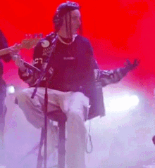a man is playing a guitar and singing into a microphone on stage .