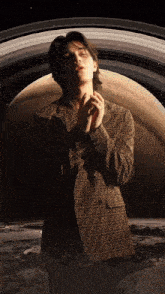 a man in a fendi jacket stands in front of a large planet