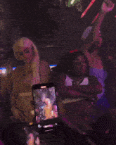 two women are dancing in a dark room with a cell phone in the foreground