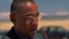 a man wearing glasses and a suit is looking down