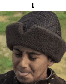 a boy wearing a fur hat with the letter l on the bottom