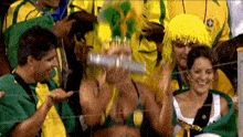 a woman wearing a yellow wig is holding a bottle in her hand while sitting in a crowd of people .