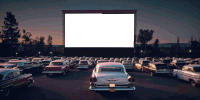 a row of old cars are parked in front of a screen that says ' hollywood ' on it