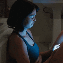a woman in a black tank top holds a blue light