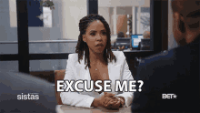 a woman sitting at a table with the words excuse me written on it