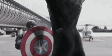 captain america is holding his shield in front of a helicopter .