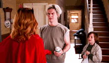 a man in a grey shirt is standing next to a woman in a red cape and a boy in a plaid jacket