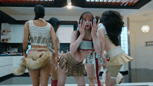 a group of women are standing in a kitchen and one has a fur tail on her back