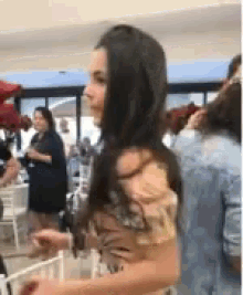 a woman with long dark hair is standing in a crowded room .