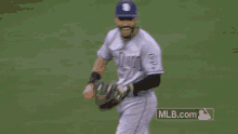a baseball player wearing a blue hat and sunglasses is running on the field .