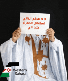 a man holding a sign that says western sahara in front of his face
