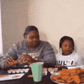 a woman and a child are sitting at a table eating nuggets .