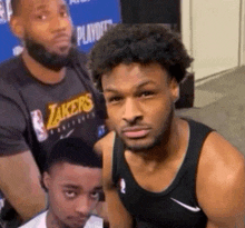 a man wearing a lakers shirt is standing next to two other men