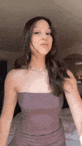 a woman in a strapless top is standing on a bed .