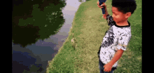 a young boy in a white and black shirt is fishing in a pond