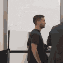 a man in a black shirt is standing next to a man in a suit