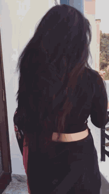 a woman 's hair is blowing in the wind and she is wearing a black top and black pants