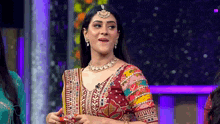 a woman in a colorful dress is standing in front of a microphone on a stage .