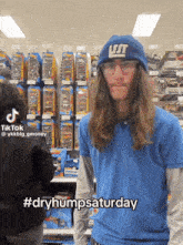 a man with long hair wearing a new york giants hat stands in a store