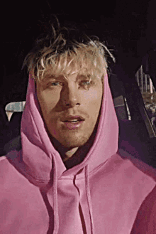 a man in a pink hoodie is sitting in the back seat of a car