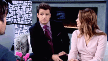 a man in a suit and tie talks to a woman in a pink dress
