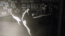a black and white image of a person 's feet on a desk