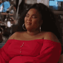 a woman in a red off the shoulder top is smiling .