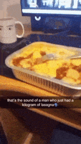 a casserole dish of lasagna with a spoon in it on a desk