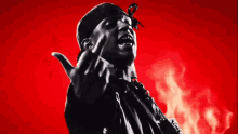 a black and white photo of a man giving the middle finger in front of flames