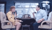 a man and a woman are sitting in chairs talking to each other .
