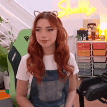 a woman with red hair and cat ears is sitting in front of a green chair