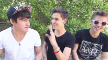 a man wearing a t-shirt that says s & r is talking to two other men