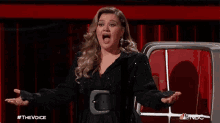 a woman with a surprised look on her face is sitting in front of a red chair .