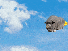 a pig is flying through a blue sky with a yellow tail