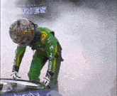 a man wearing a helmet and a green jacket is standing next to a car with ries written on it