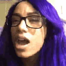 a close up of a woman wearing glasses and purple hair .