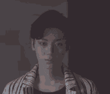 a young man wearing a striped shirt and a towel around his neck .